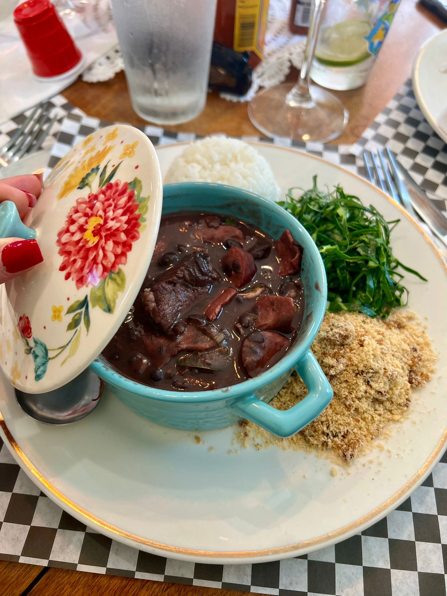 Brazilian feijoada with rice, collard greens and farofa in a turquoise bowl